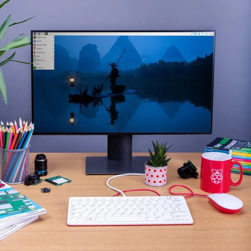 Foto de uma área de trabalho Raspberry Pi em uma mesa com teclado, mouse e artigos de papelaria